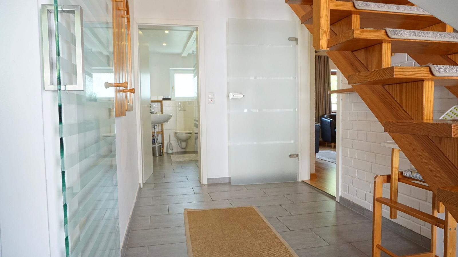 Haus mit Holztreppe, Glaswand und Bad im Flur