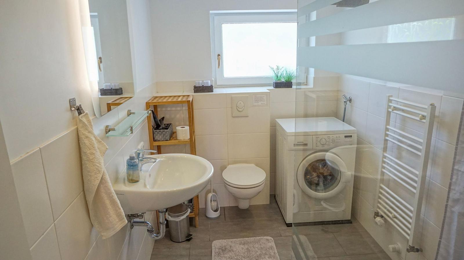 Badezimmer mit Waschmaschine, Toilette und Spiegel