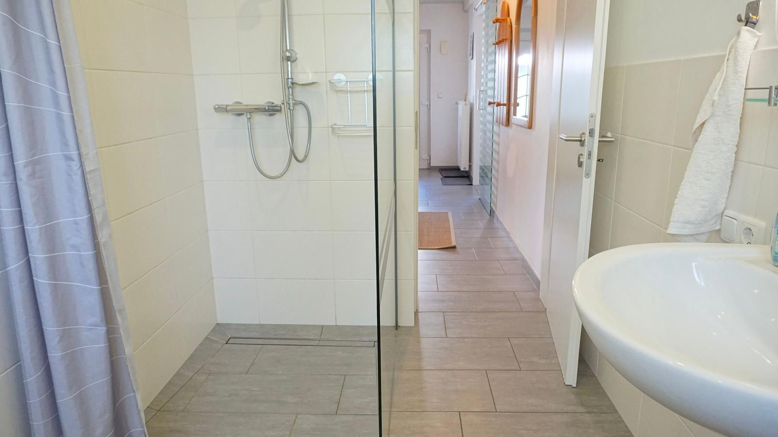 Bad mit Dusche, Waschbecken und Handtuchhalter.