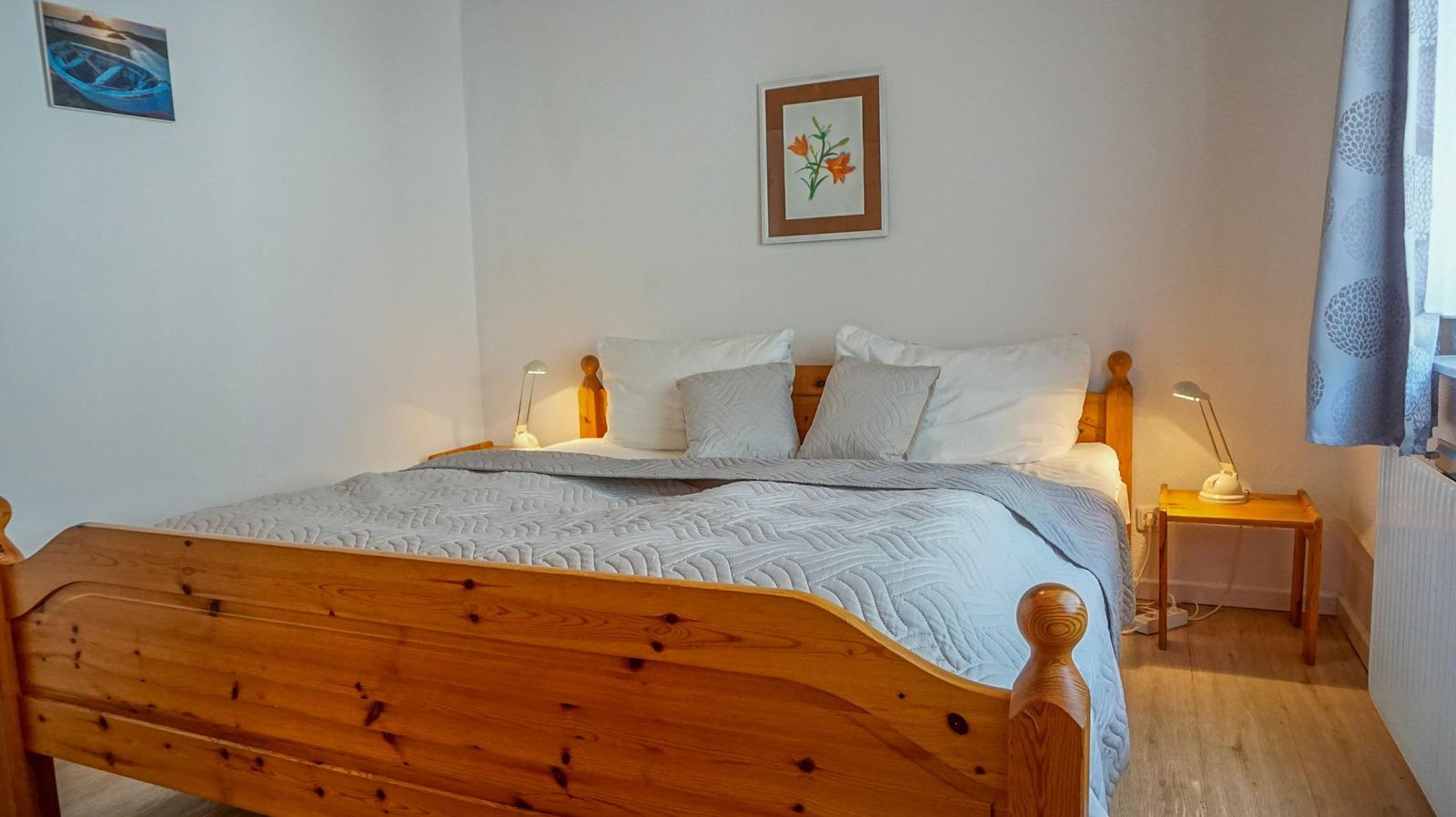 Ein Schlafzimmer mit Holzbett, zwei Nachttischen und Wandbildern.