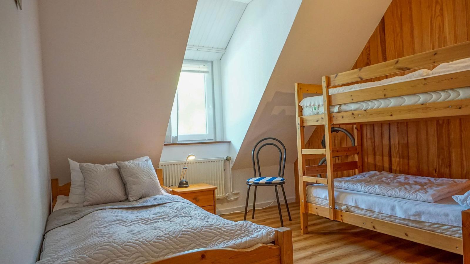 Schlafzimmer mit Doppelbett und Kletterkorb. Holzbett, Fenster und Stuhl.