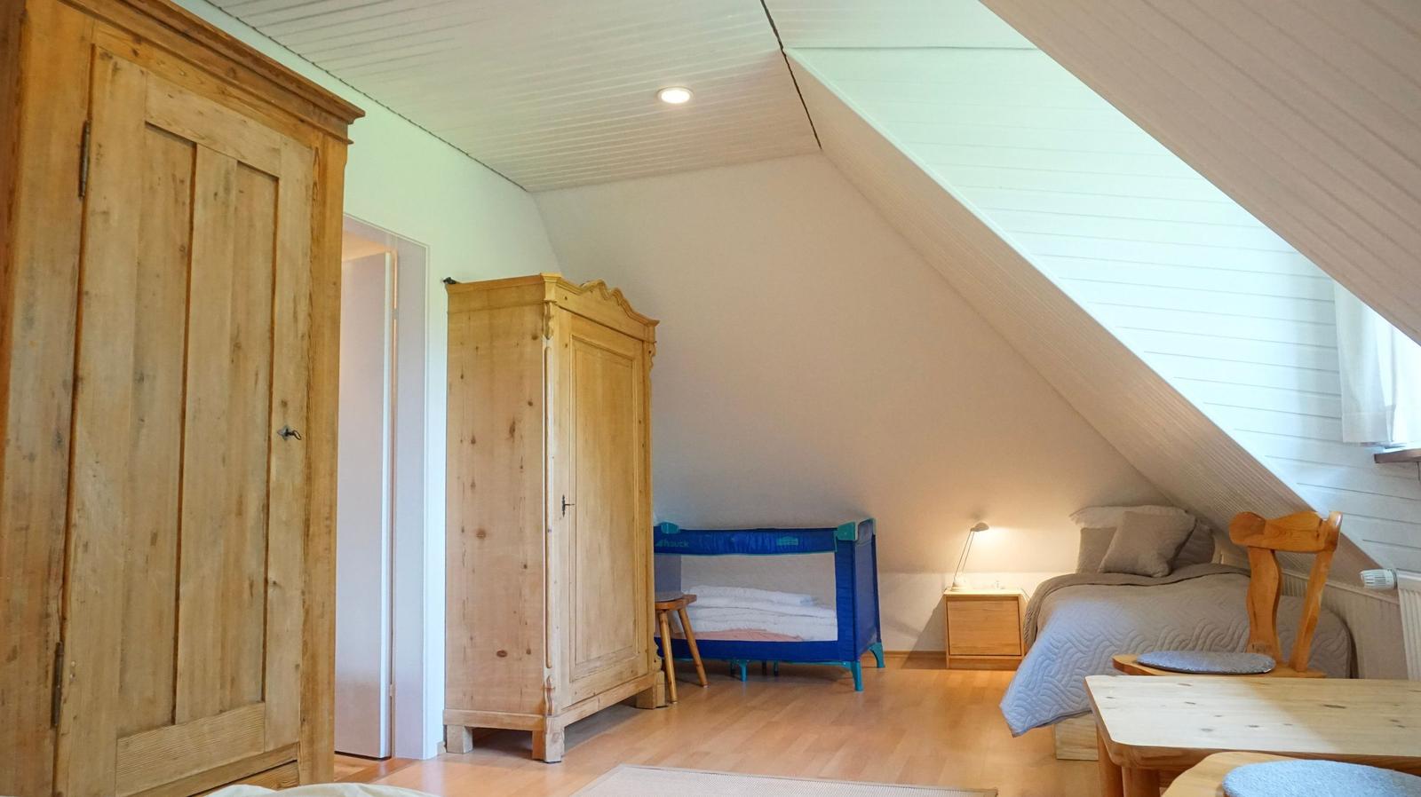 Schlafzimmer mit Holzmöbeln, Babybett und Dachschräge