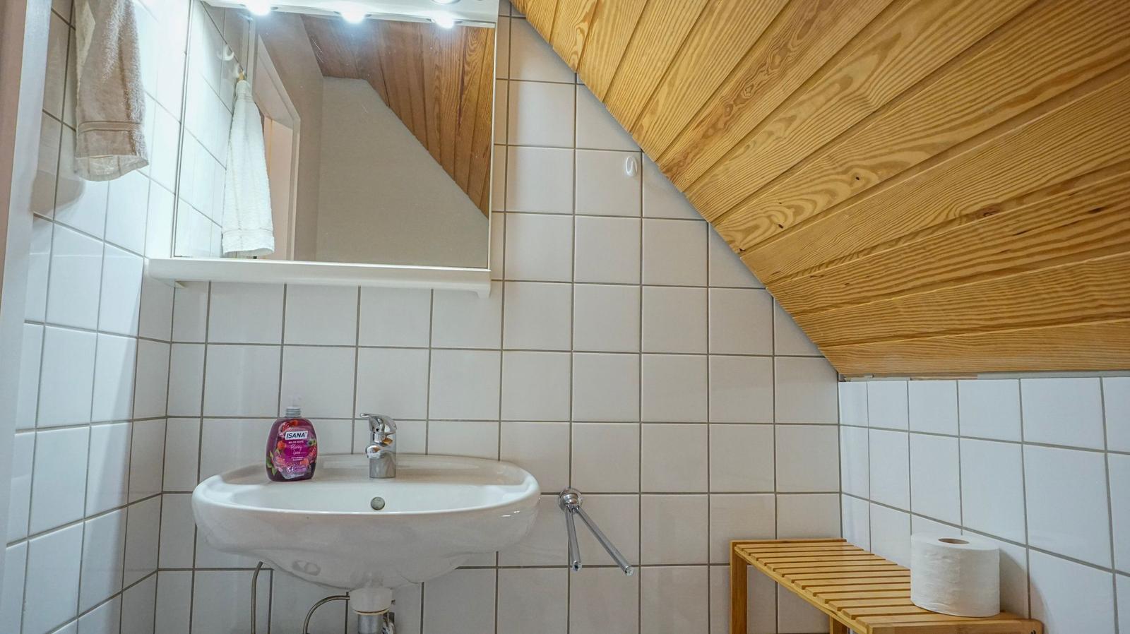 Badezimmer mit Waschbecken, Spiegel und Holzdecke