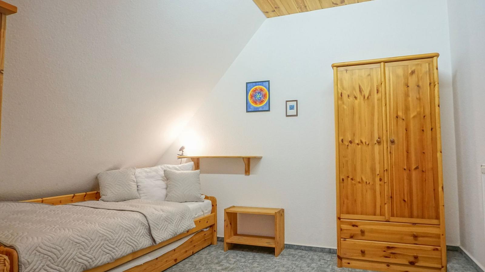 Bedroom with wooden bed, wardrobe, and wall art.