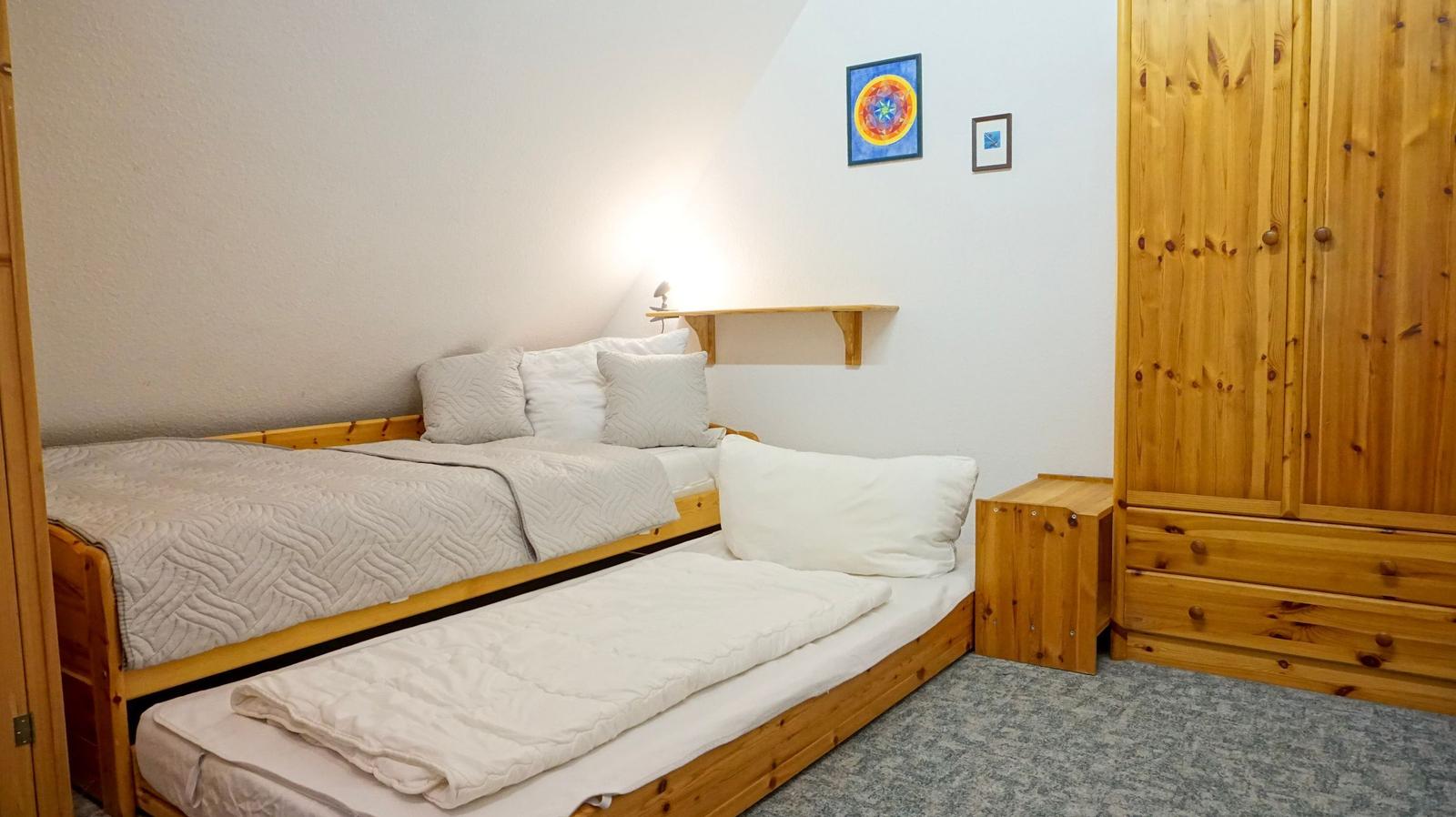 Room with two beds, wooden furniture, and wall pictures.
