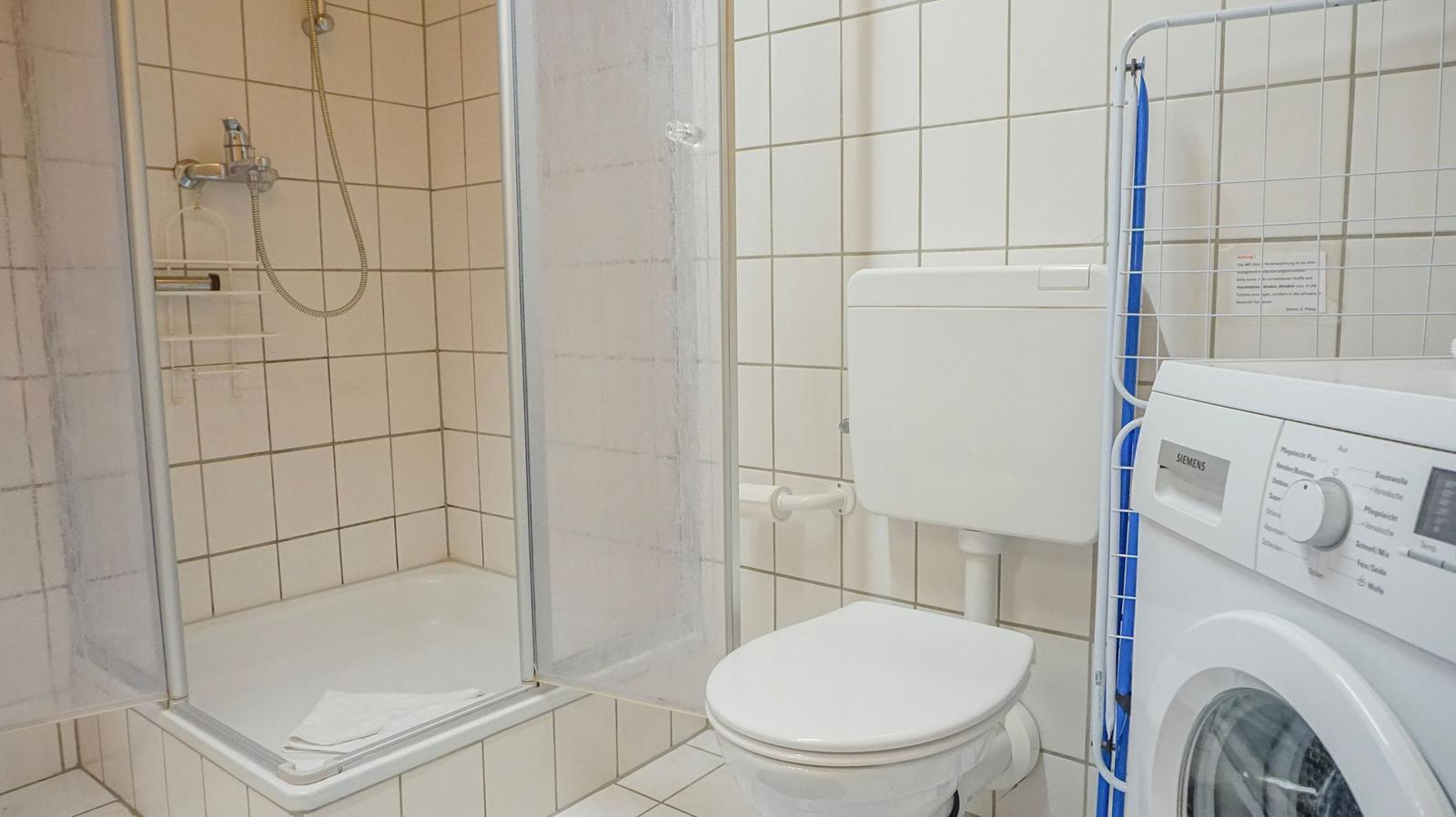 Bathroom with shower, toilet, and washing machine.