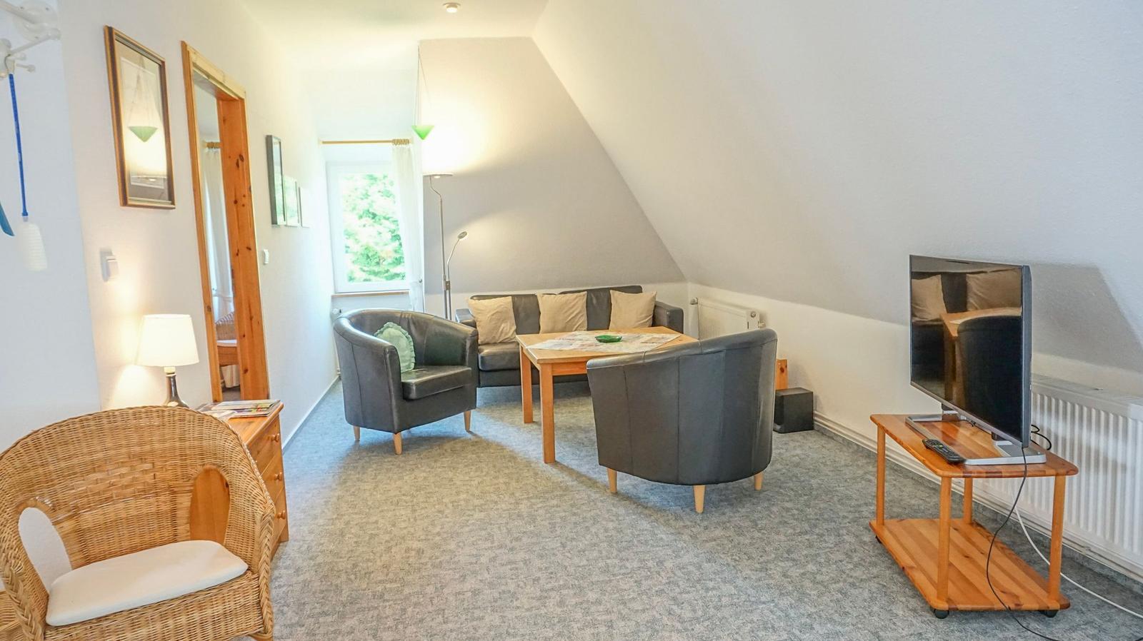 Living room with sofa, two chairs, table, and TV on wooden stand
