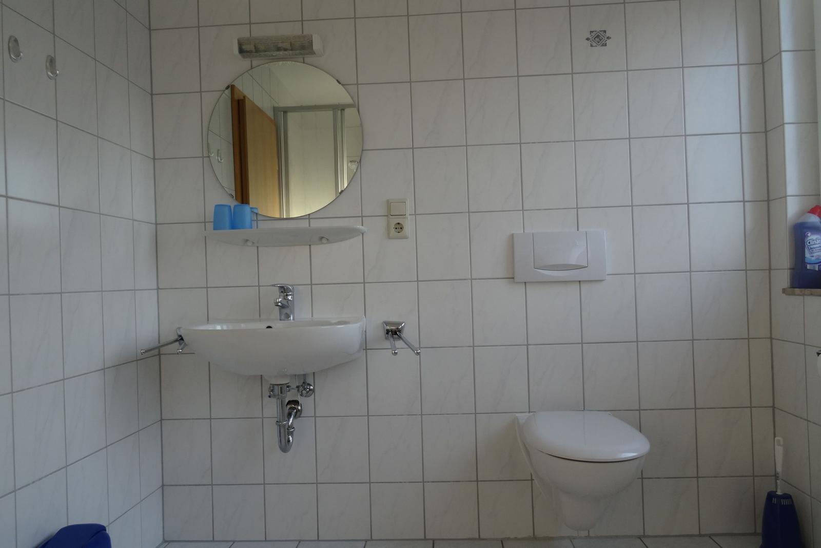 Badezimmer mit Waschbecken, Toilette und runden Spiegel