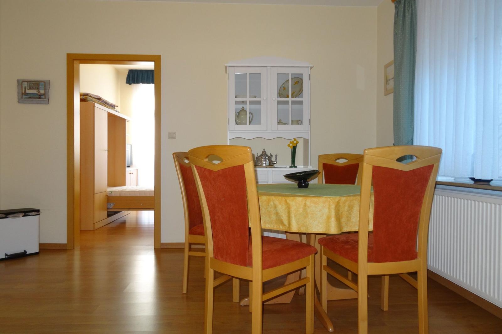 Esszimmer mit Tisch, Stühlen und Schrank. Durchgang zum Schlafzimmer.