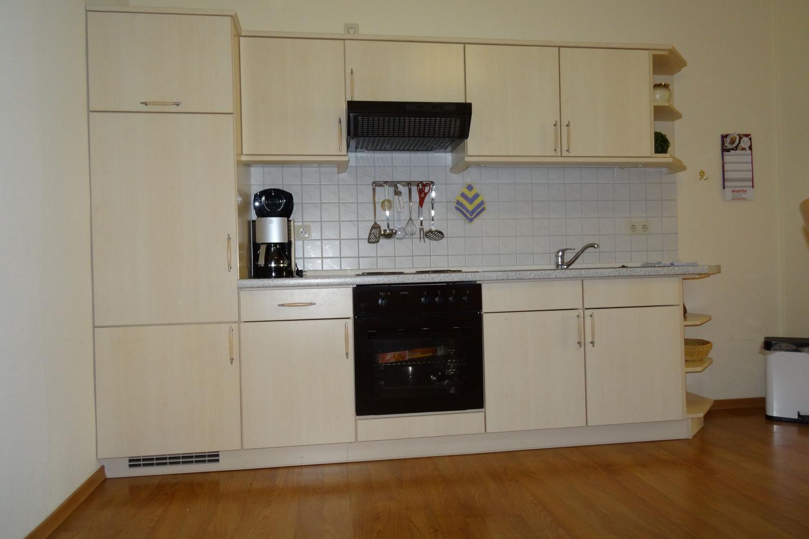 Küche mit Holzschrank, Herd und Spüle
