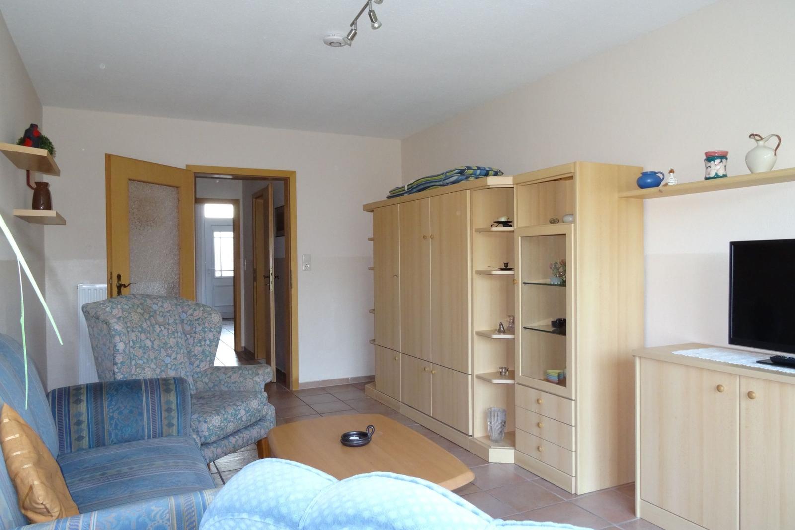 Wohnzimmer mit Sofa, Sessel, Couchtisch und Holzmöbeln.