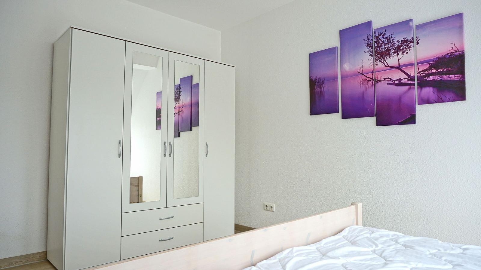 Schlafzimmer mit weißem Schrank und Wandbild