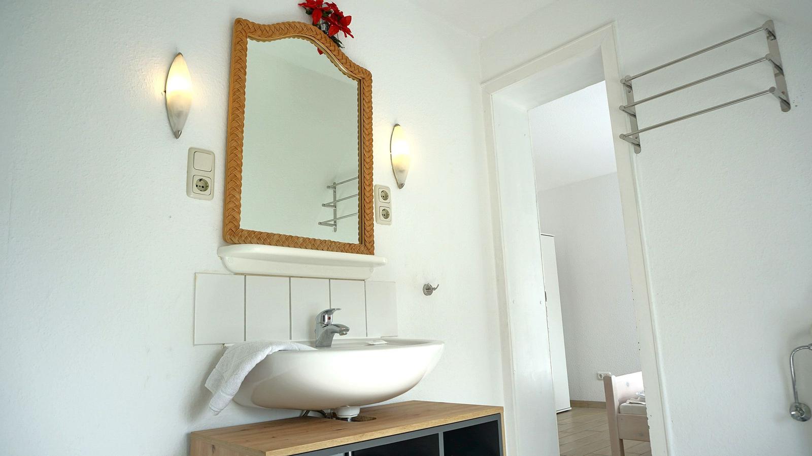 Badezimmer mit Waschbecken, Spiegel und Handtuchhalter.