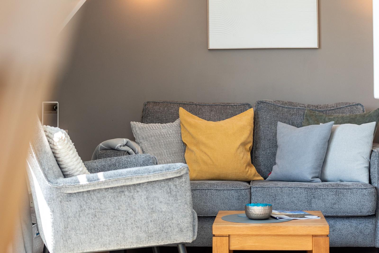 Ein grauer Sofa mit Kissen und einem Holztisch im Wohnbereich.