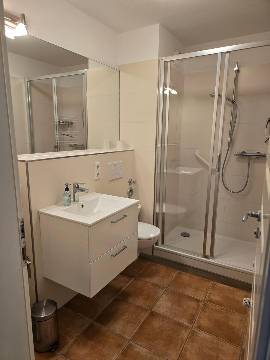 Badezimmer mit Dusche, Waschbecken und Toilette.