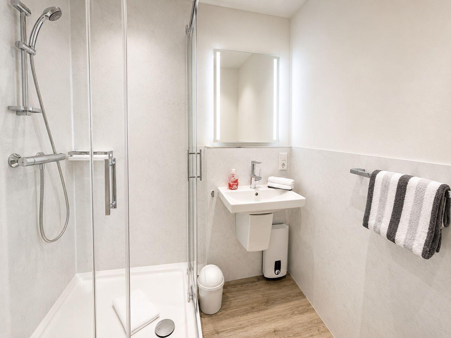 Badezimmer mit Dusche, Waschbecken und Handtuchhalter.