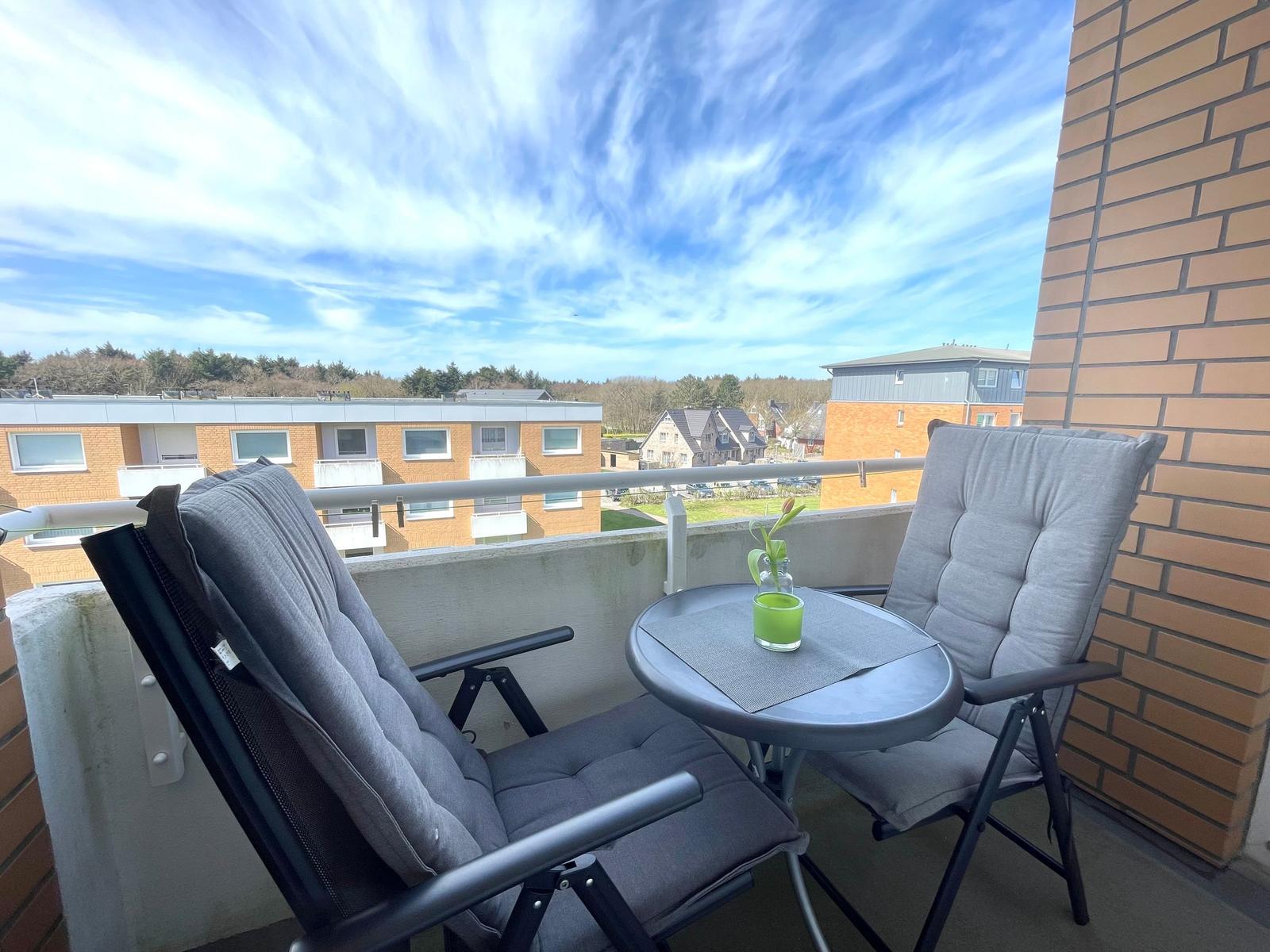 Terrasse mit zwei Stühlen und Tisch. Hintergrund: Gebäude und Himmel.