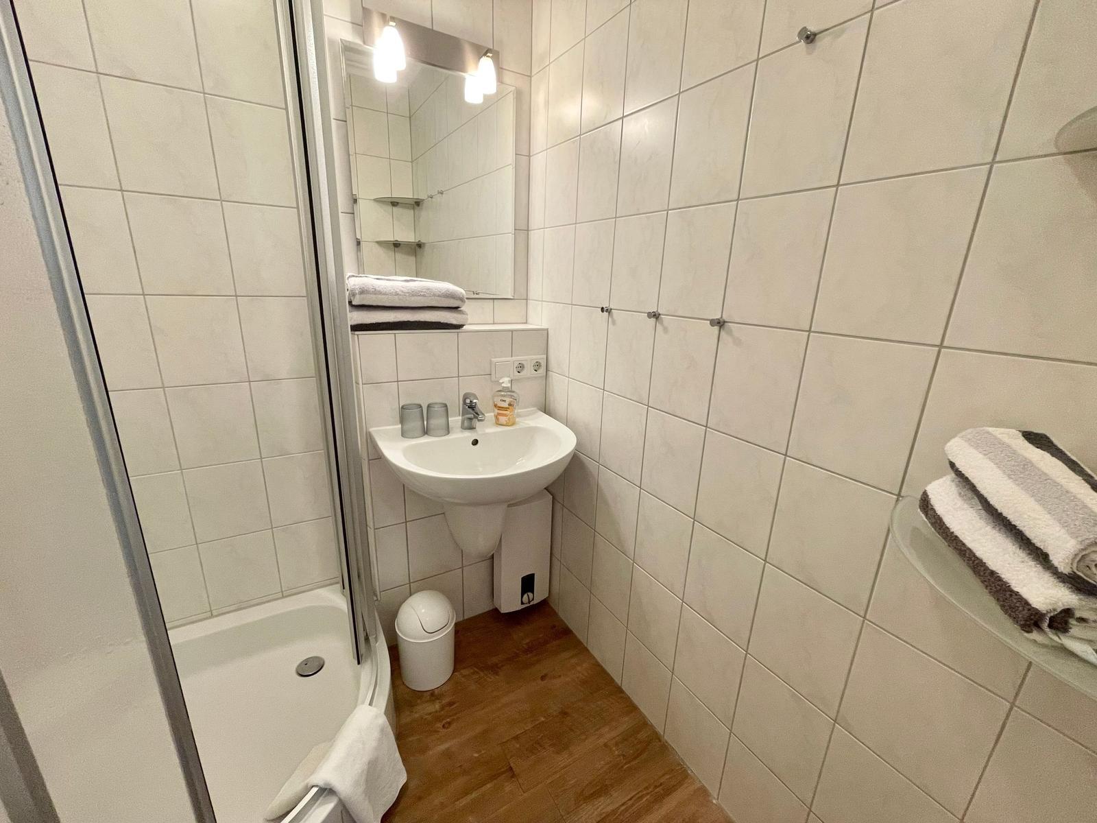 Badezimmer mit Dusche, Waschbecken und Handtüchern