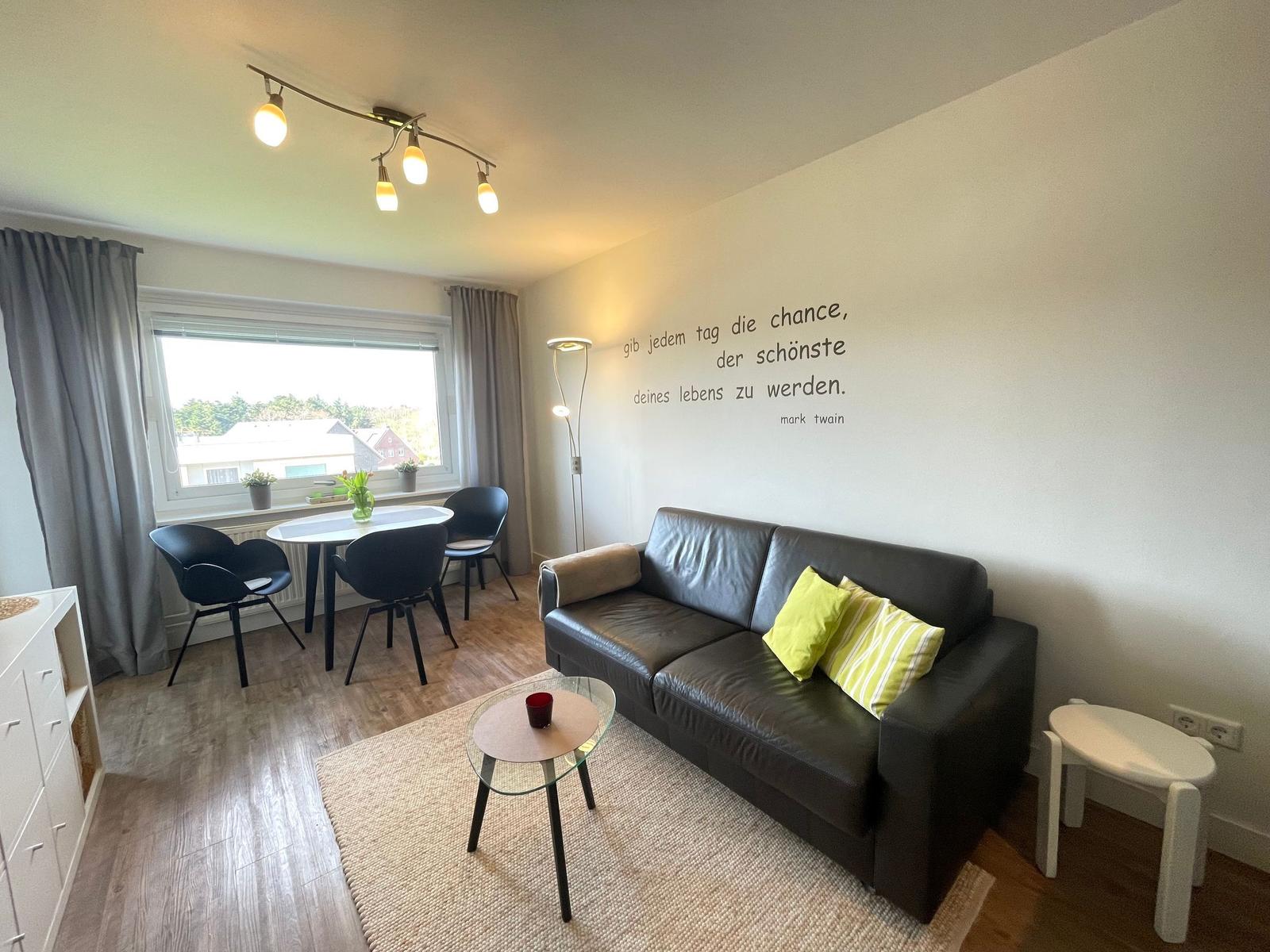 Wohnzimmer mit Sofa, Esstisch und Wanddekoration.