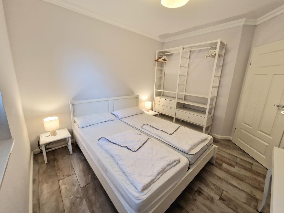 Schlafzimmer mit Doppelbett, Kleiderschrank und Nachttischen.