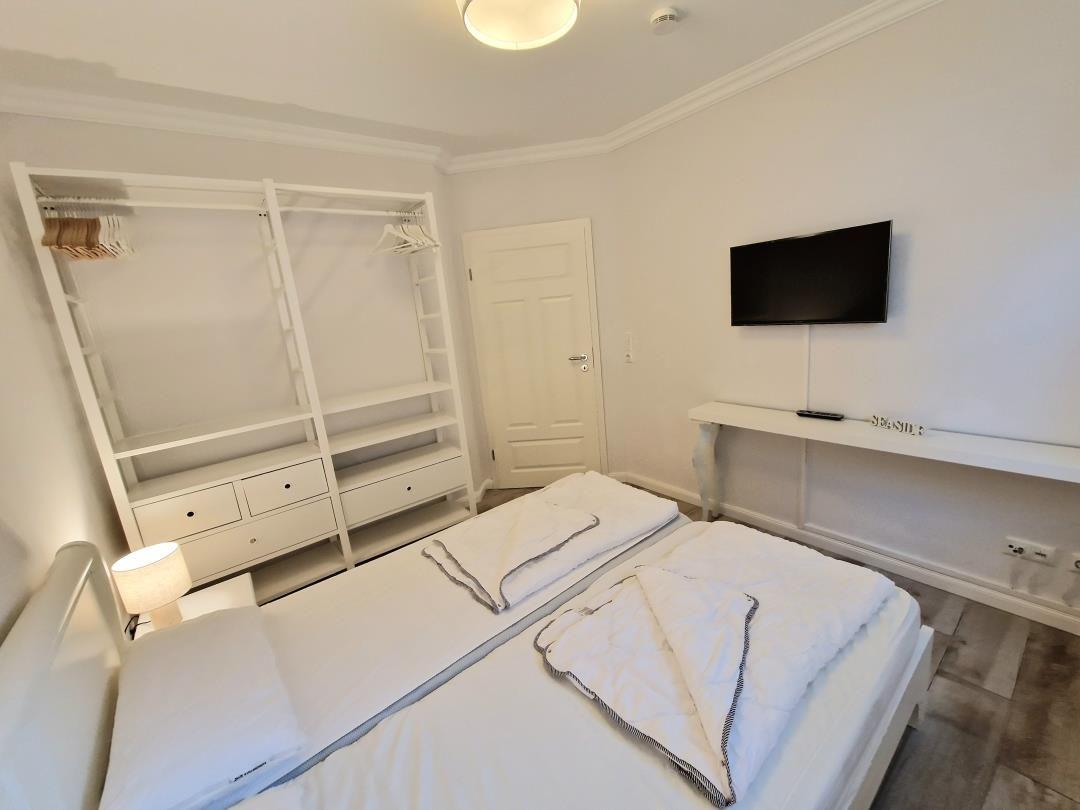 Schlafzimmer mit Doppelbett, Kleiderschrank und Wand-TV