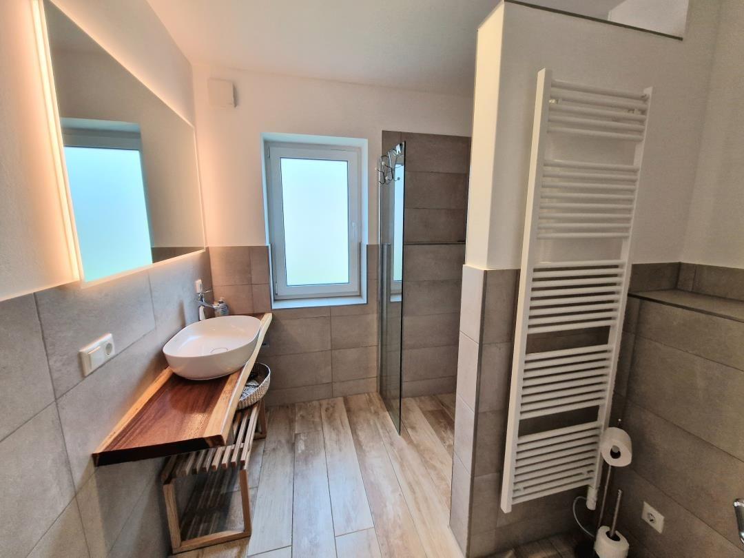 Badezimmer mit Waschbecken, Dusche und Heizkörper