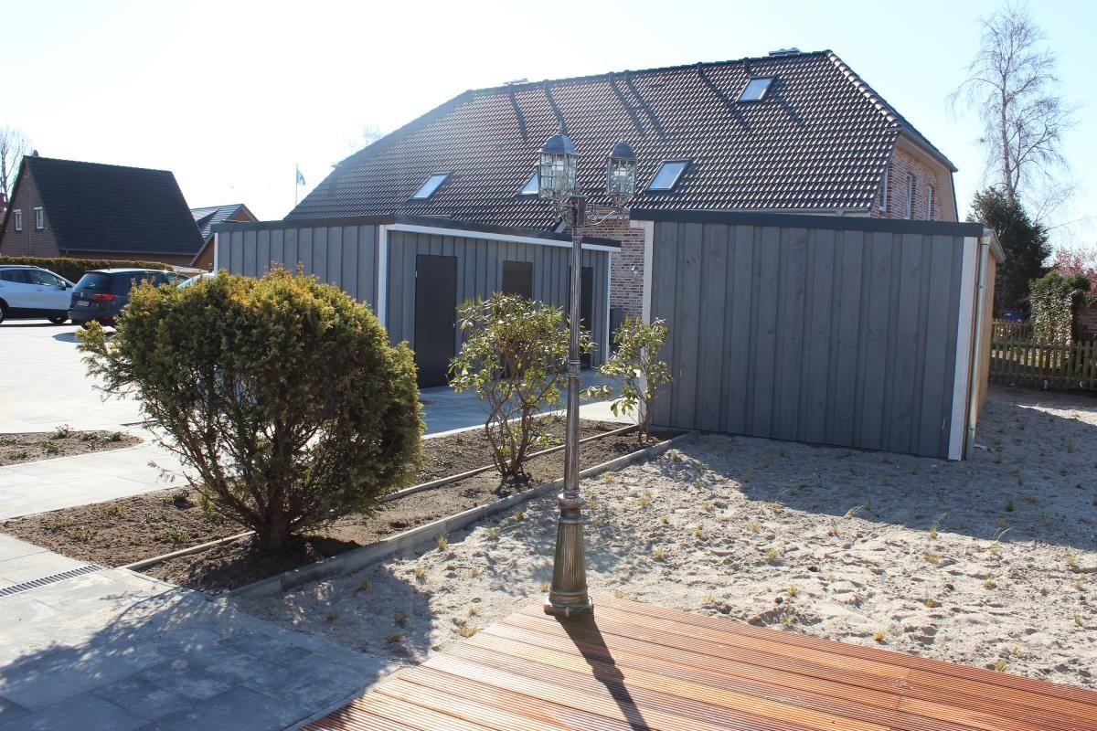 Moderne Villa mit Holzterrasse und gepflegtem Gartenbereich.