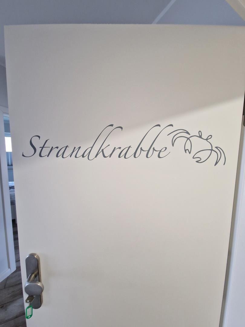 Türe mit Aufschrift Strandkrabbe und Krabbenmotiv.