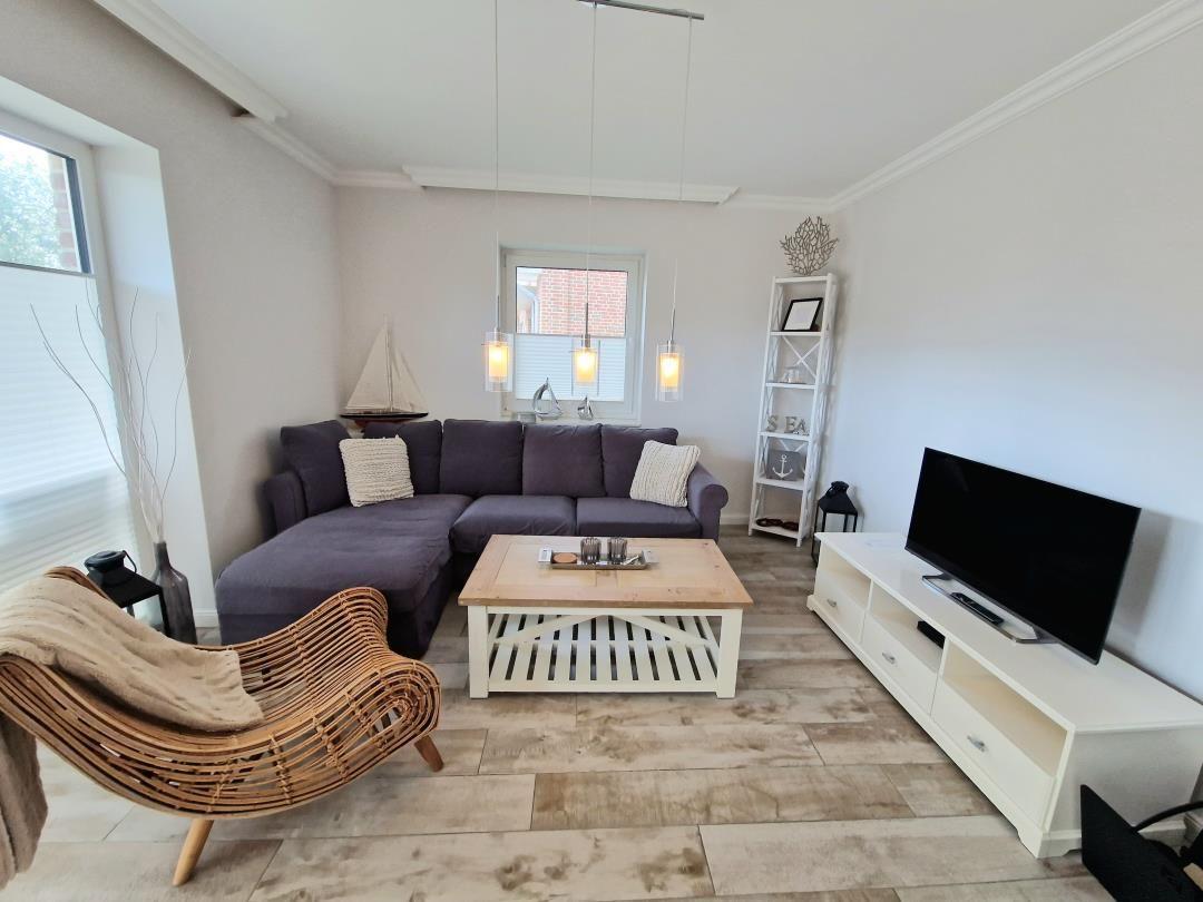 Wohnzimmer mit Ecksofa, TV-Bodenregal und Holztisch.