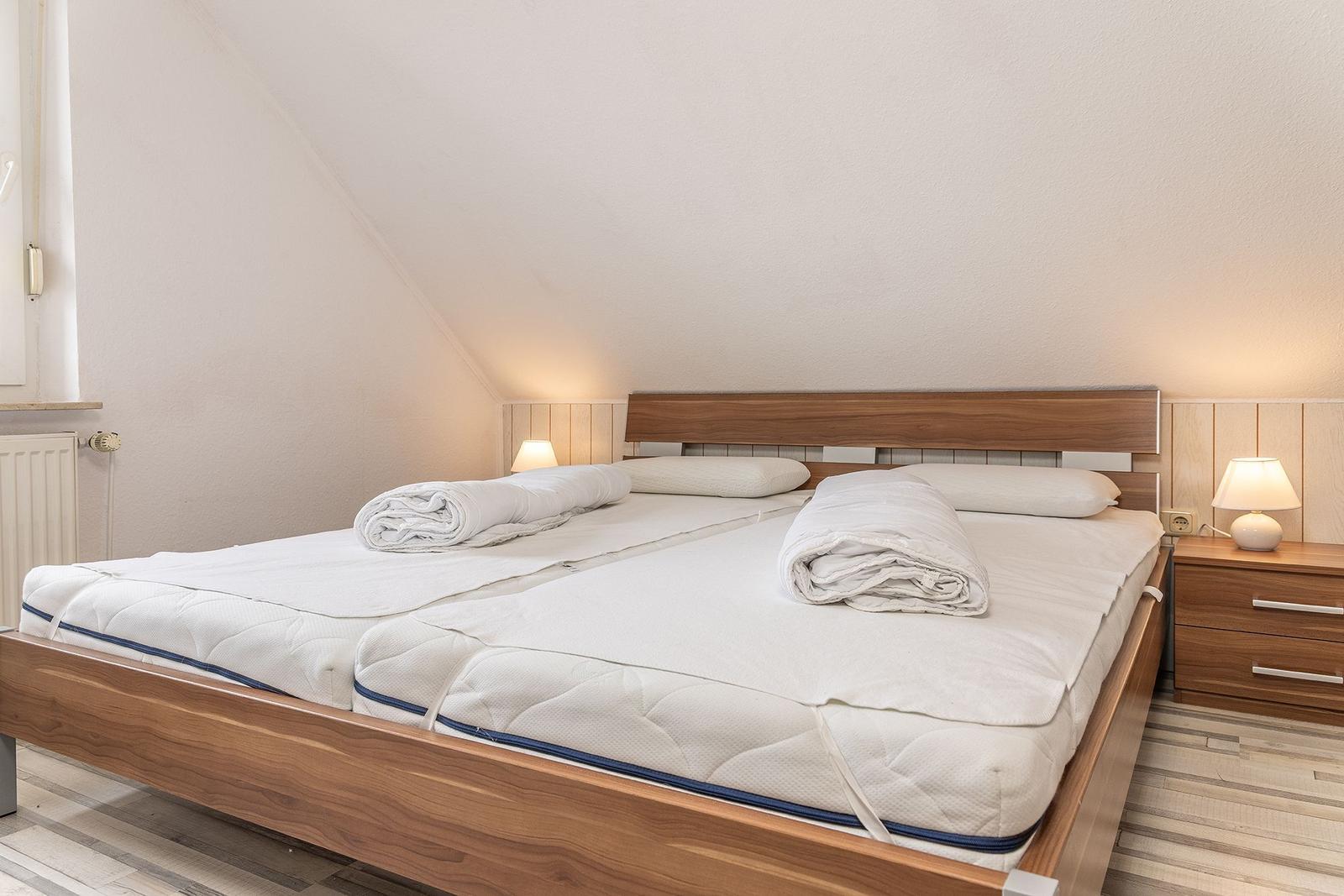 Schlafzimmer mit Doppelbett, Holzrahmen, zwei Nachttischen und Lampen.