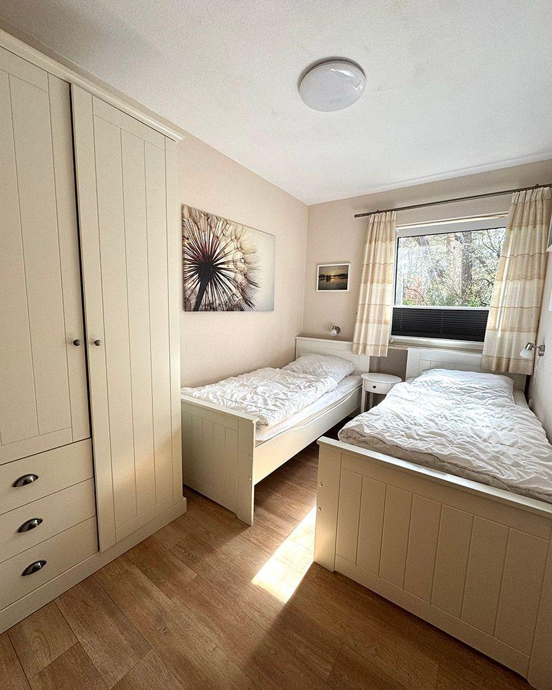 Zimmer mit zwei Betten, Schrank und Fenster mit Blick auf die Natur.