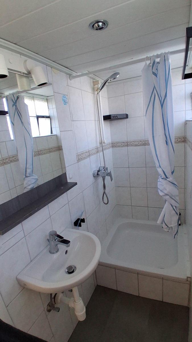 Badezimmer mit Dusche, Waschbecken und Spiegel