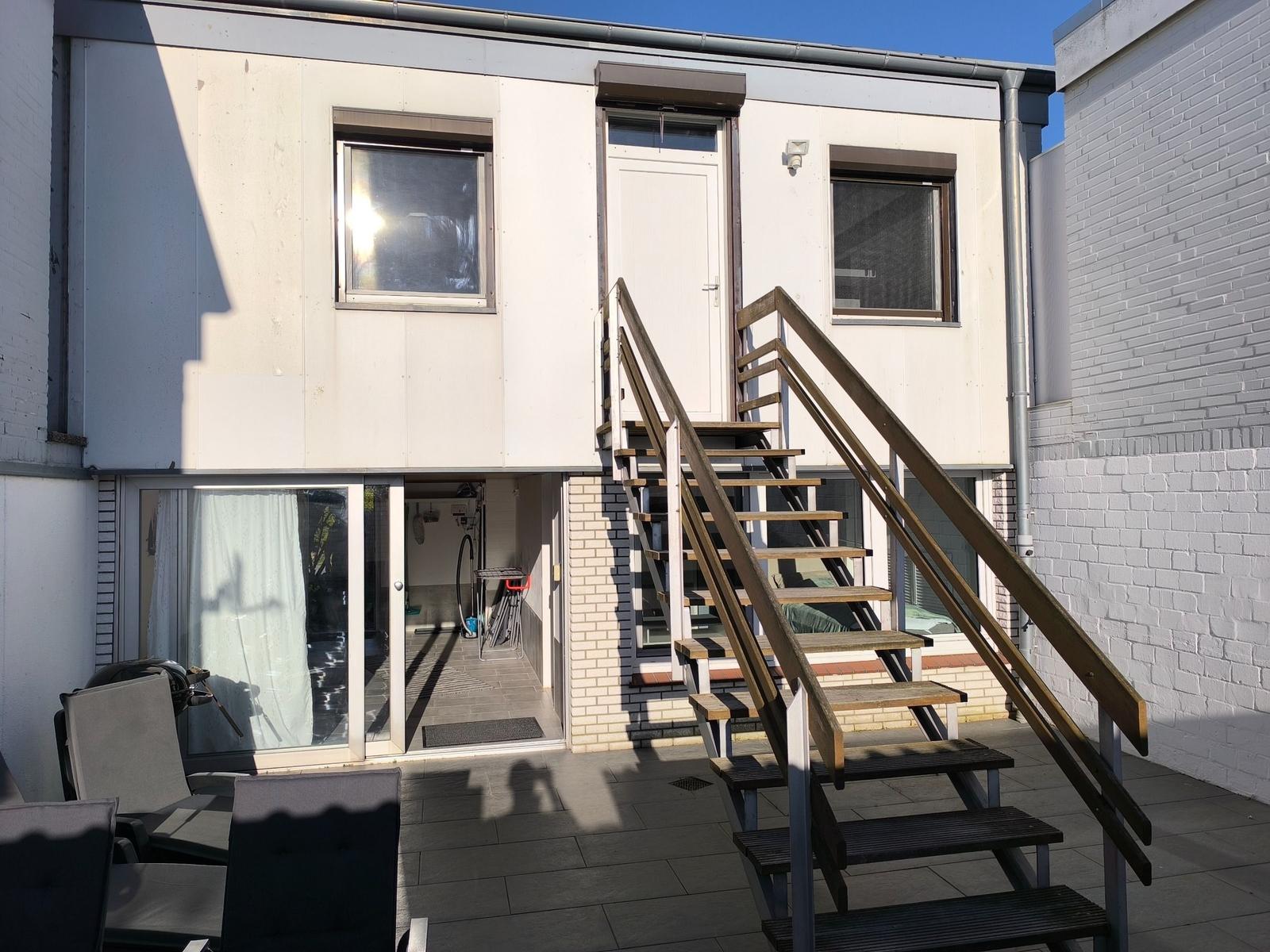 Haus mit Außentreppe, Terrasse und Glasfront zur Garage.