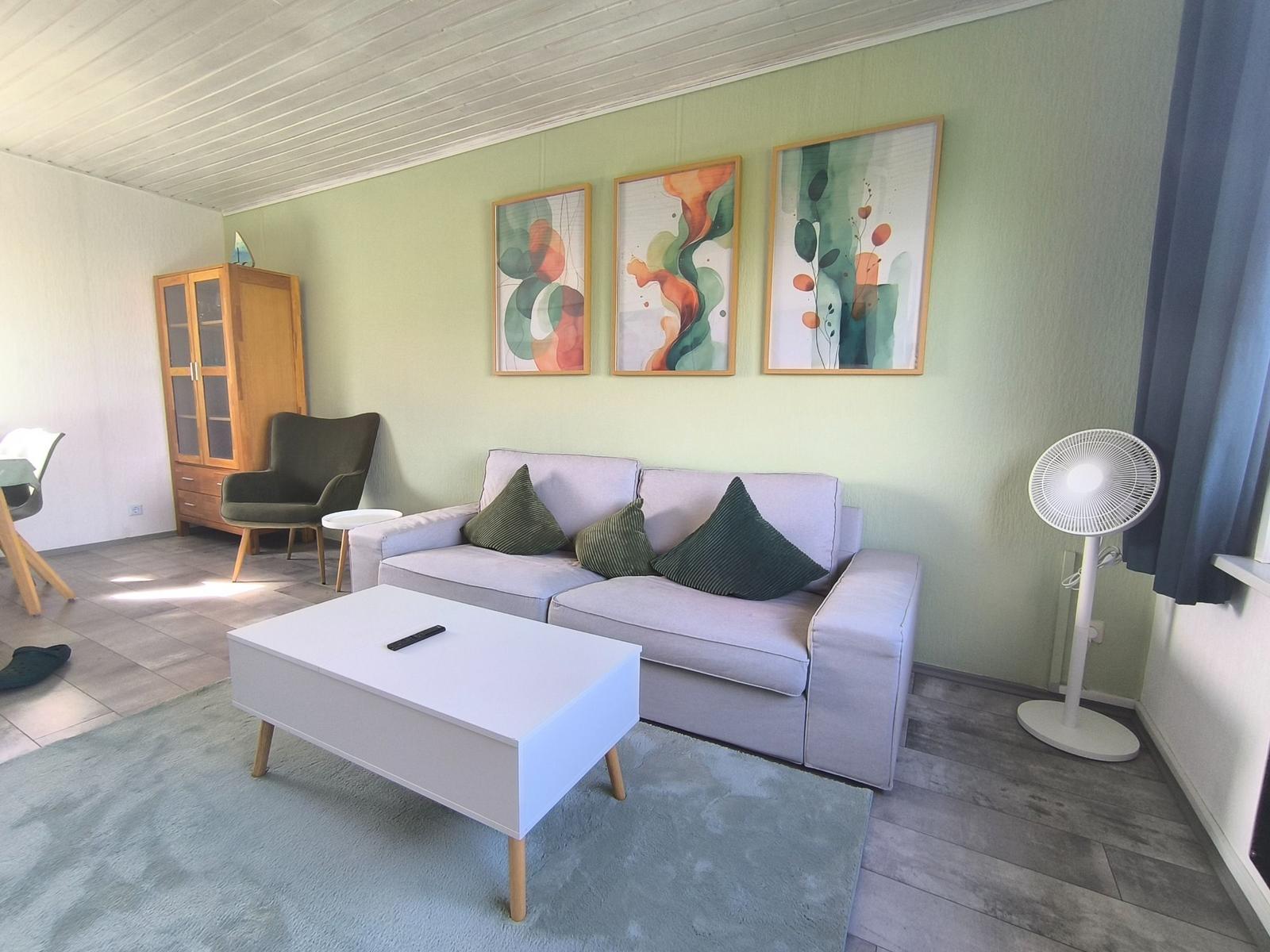 Wohnzimmer mit Sofa, Couchtisch und Wandbildern.