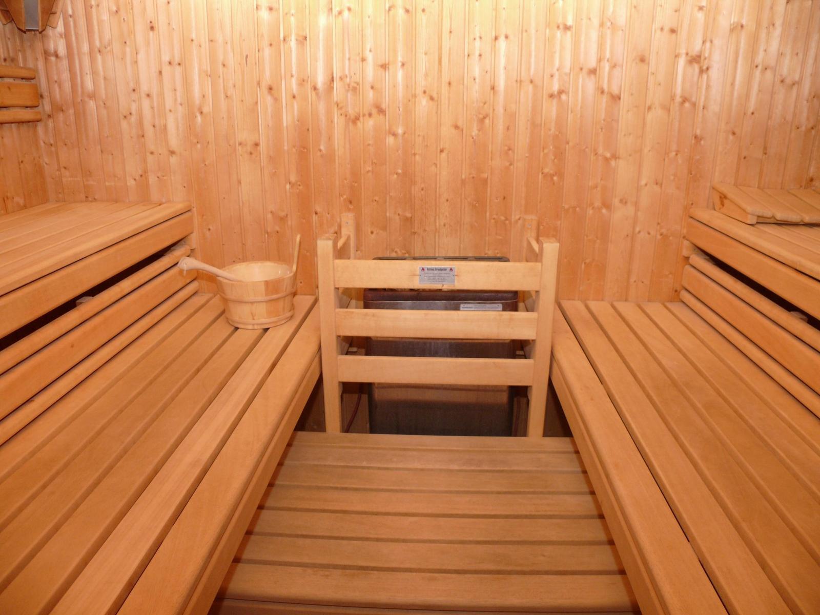 Sauna mit Holzbank, Holzwand und Holzschale.