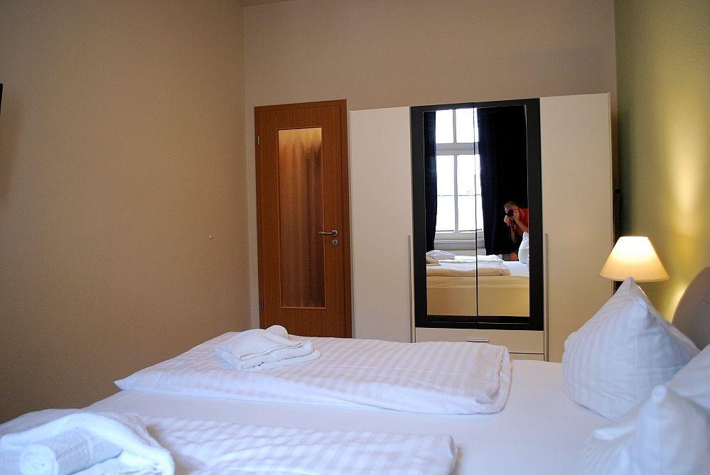 Schlafzimmer mit Bett, Spiegelschrank und Lampe.