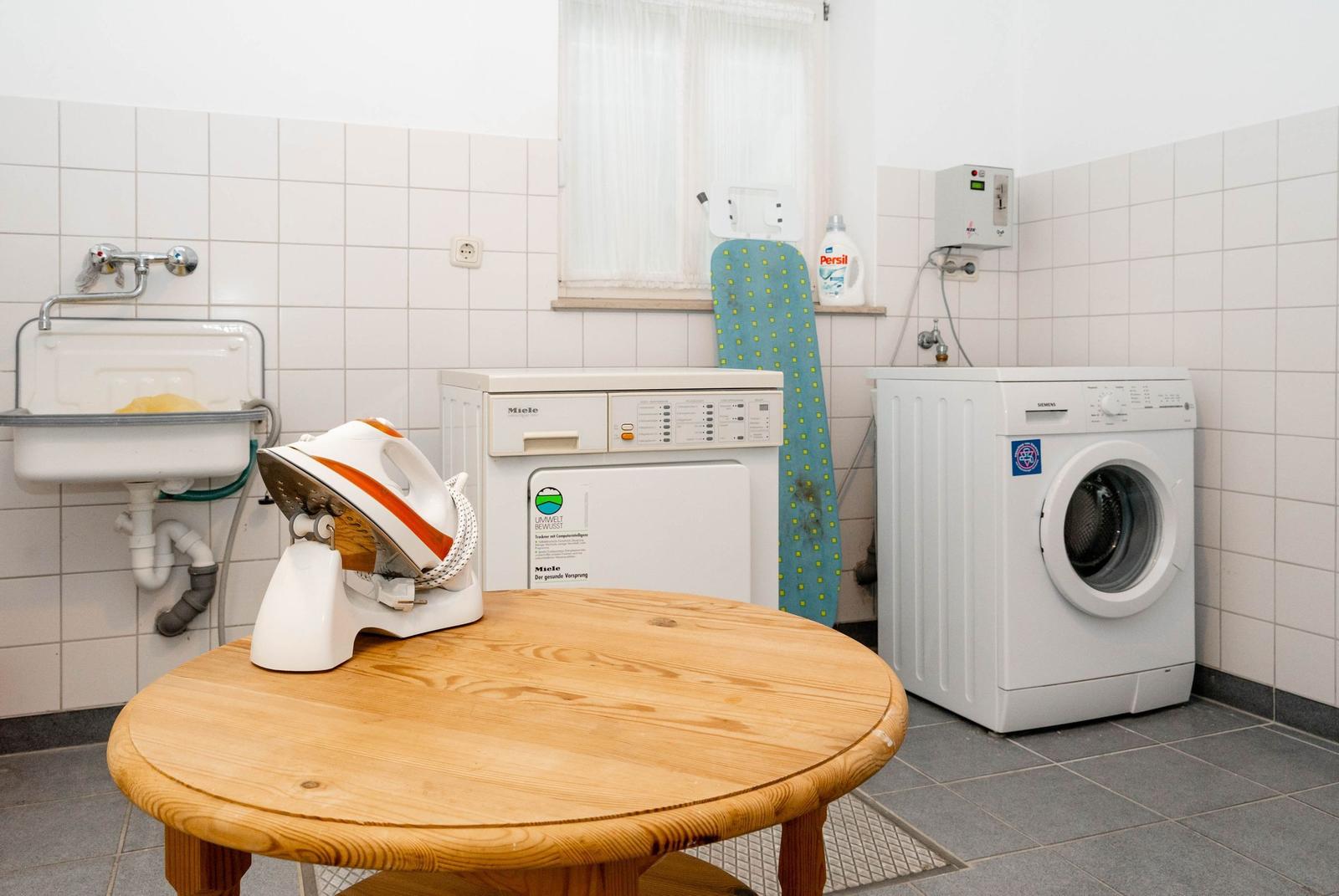 Wasch- und Trocknerbereich mit Waschmaschine, Trockner und Bügelschrank.