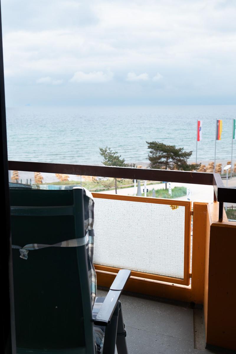 Blick von Balkon auf Meer mit Stuhl und Geländer