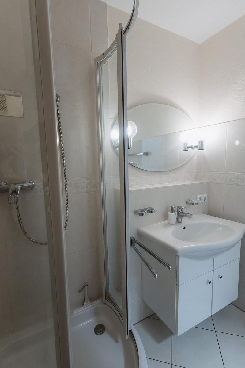 Badezimmer mit Dusche, Waschbecken und Spiegel