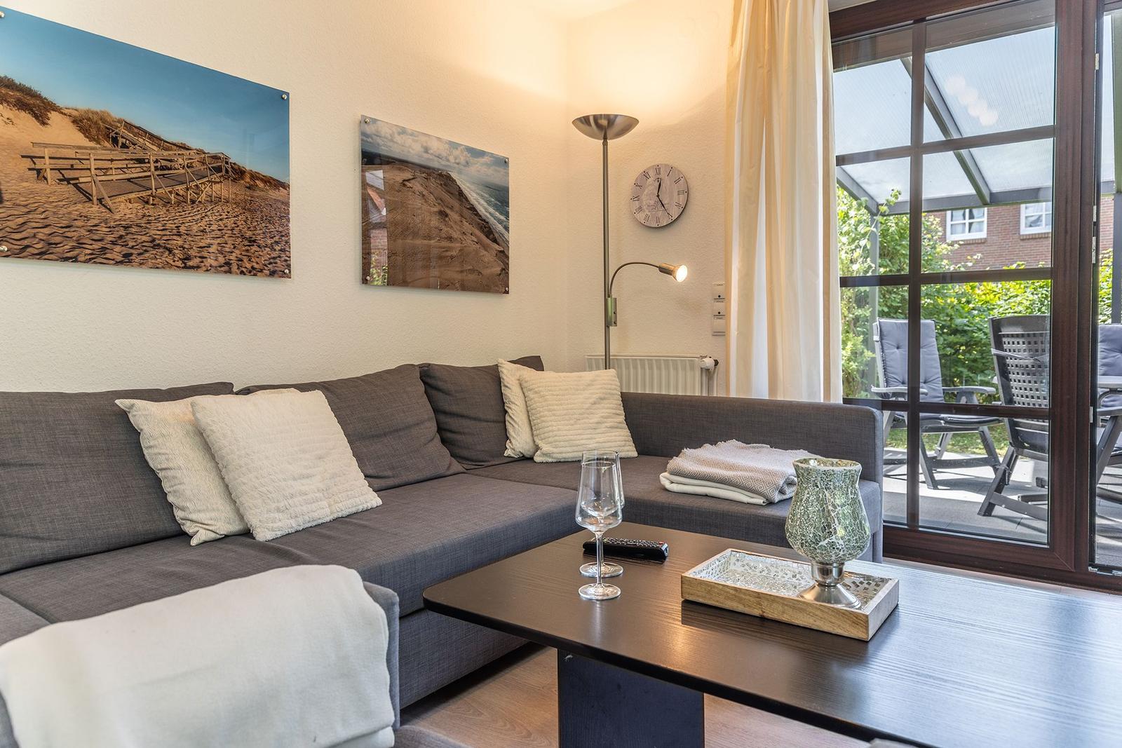 Ein Wohnzimmer mit Sofa, Tisch und Blick auf eine Terrasse.