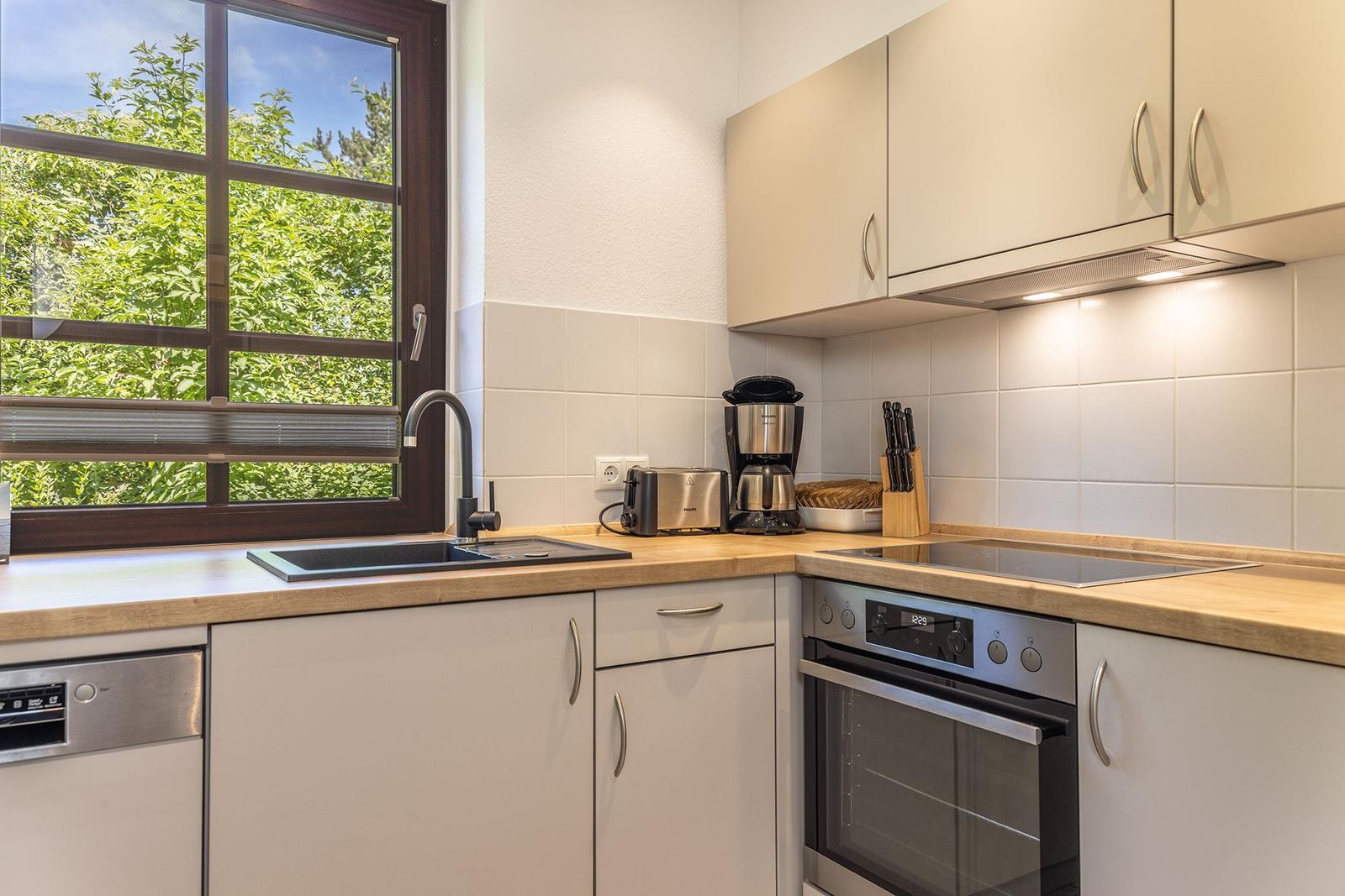 Küche mit Holzoberflächen, Edelstahlgeräten und Fensterblick auf Grün.