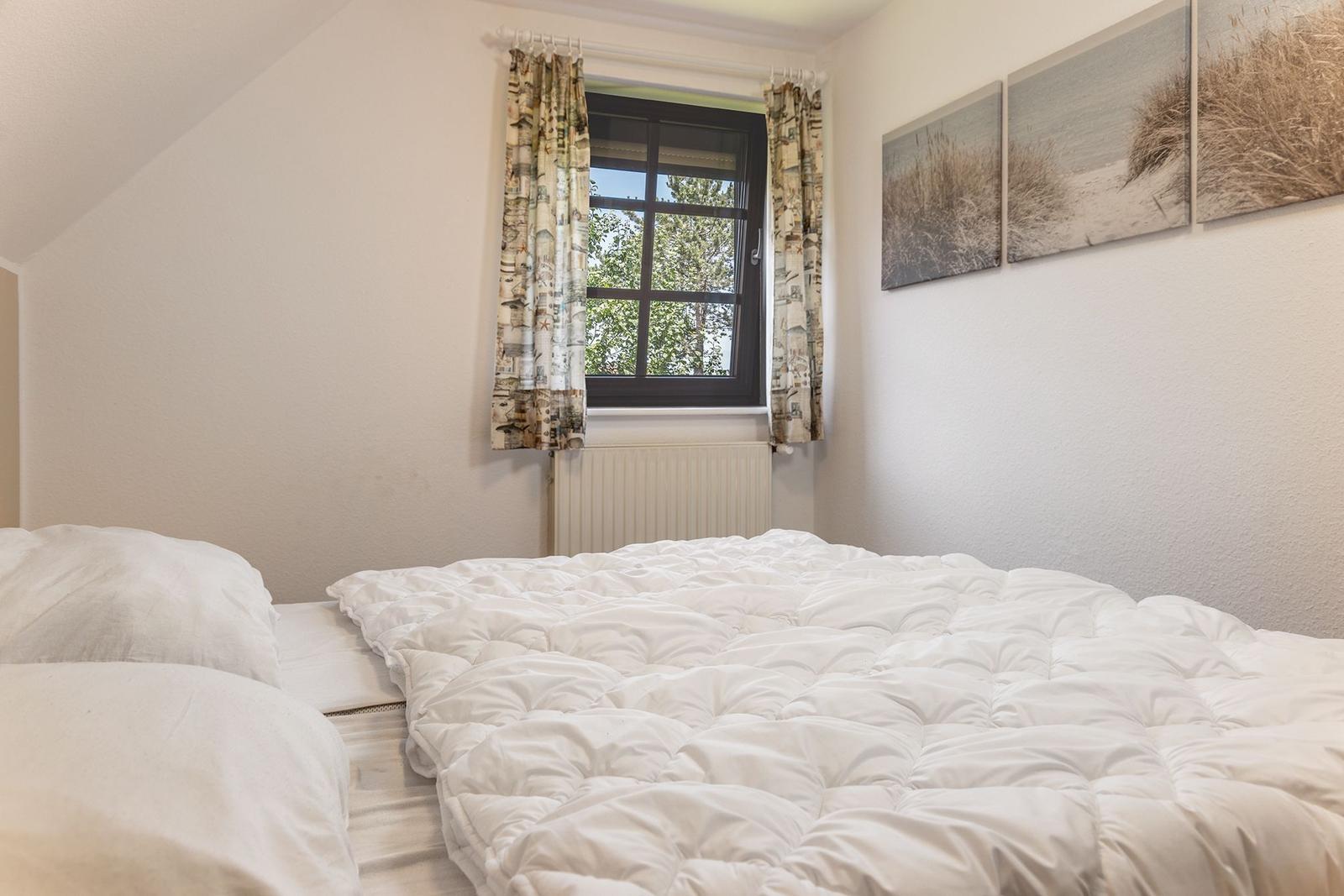 Schlafzimmer mit Bett, Fenster und Wandbildern