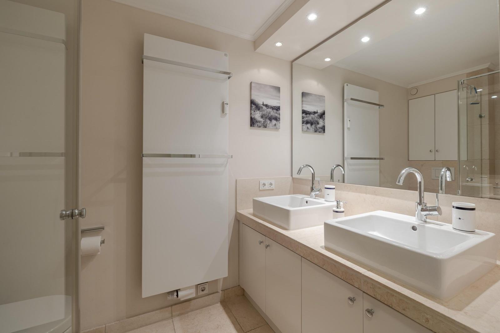 Badezimmer mit zwei Waschbecken, Spiegelschrank und Duschabtrennung.