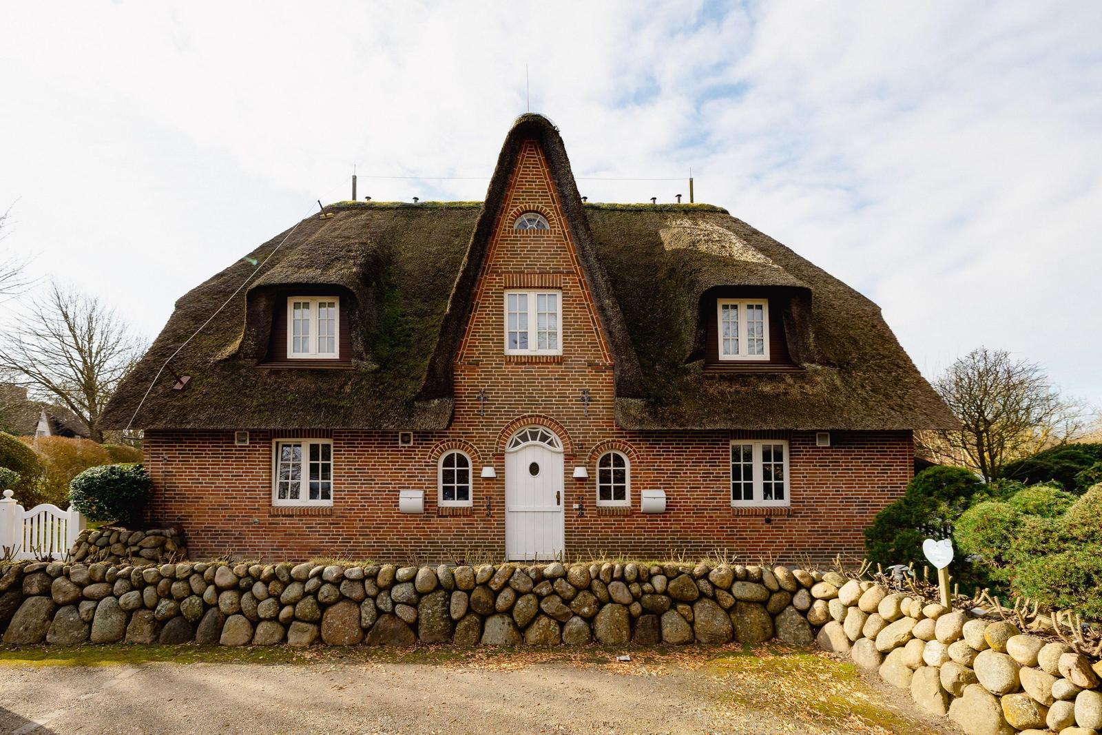 Ein Haus mit strohgedecktem Dach und rotem Ziegelsteinbau.