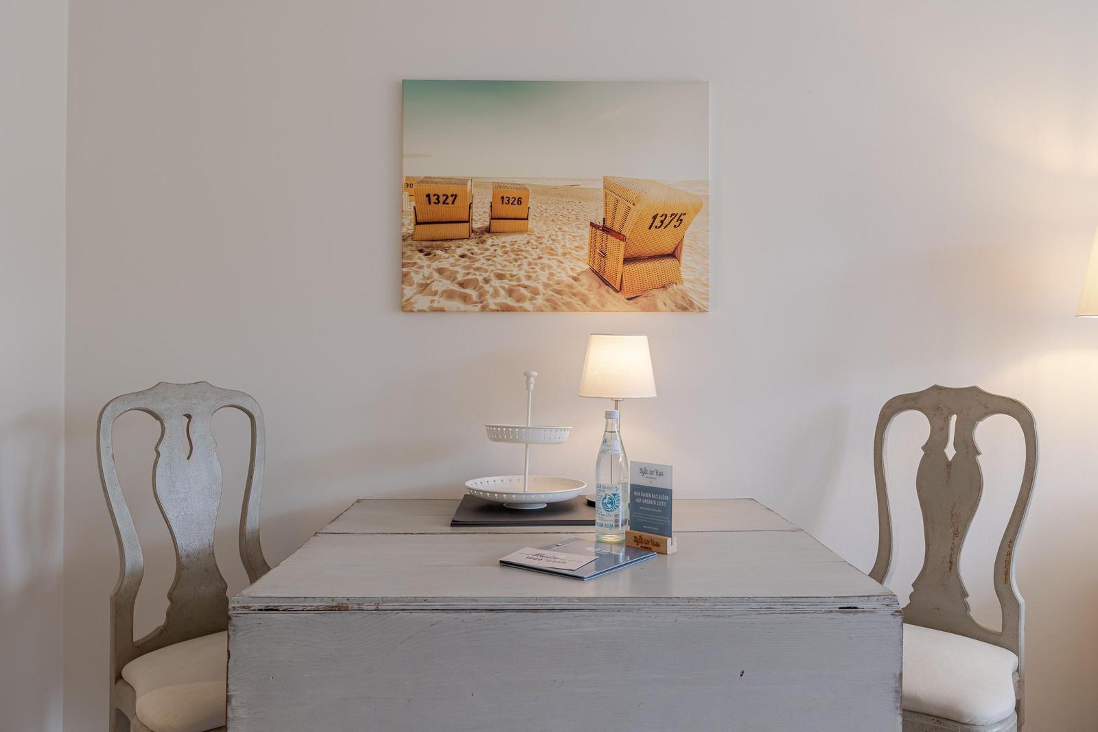 Ein Tisch mit zwei Stühlen und einer Wanddekoration mit Strandstühlen.