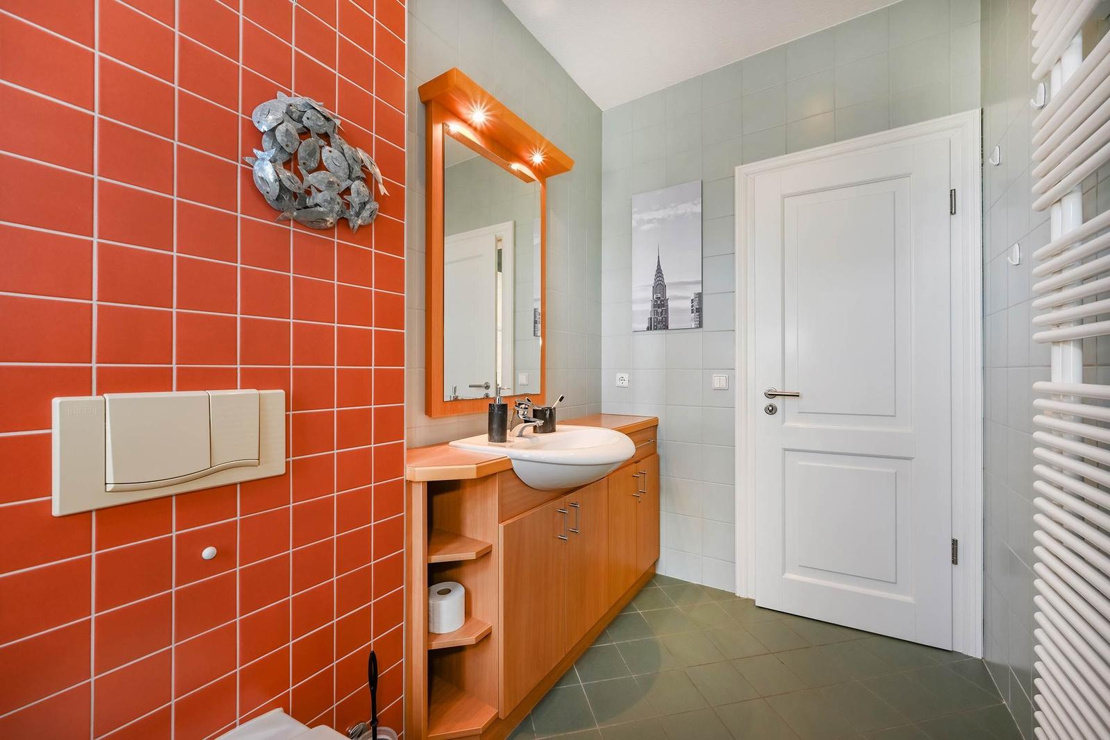 Badezimmer mit orangefarbener Wand, Spiegel und Waschtisch