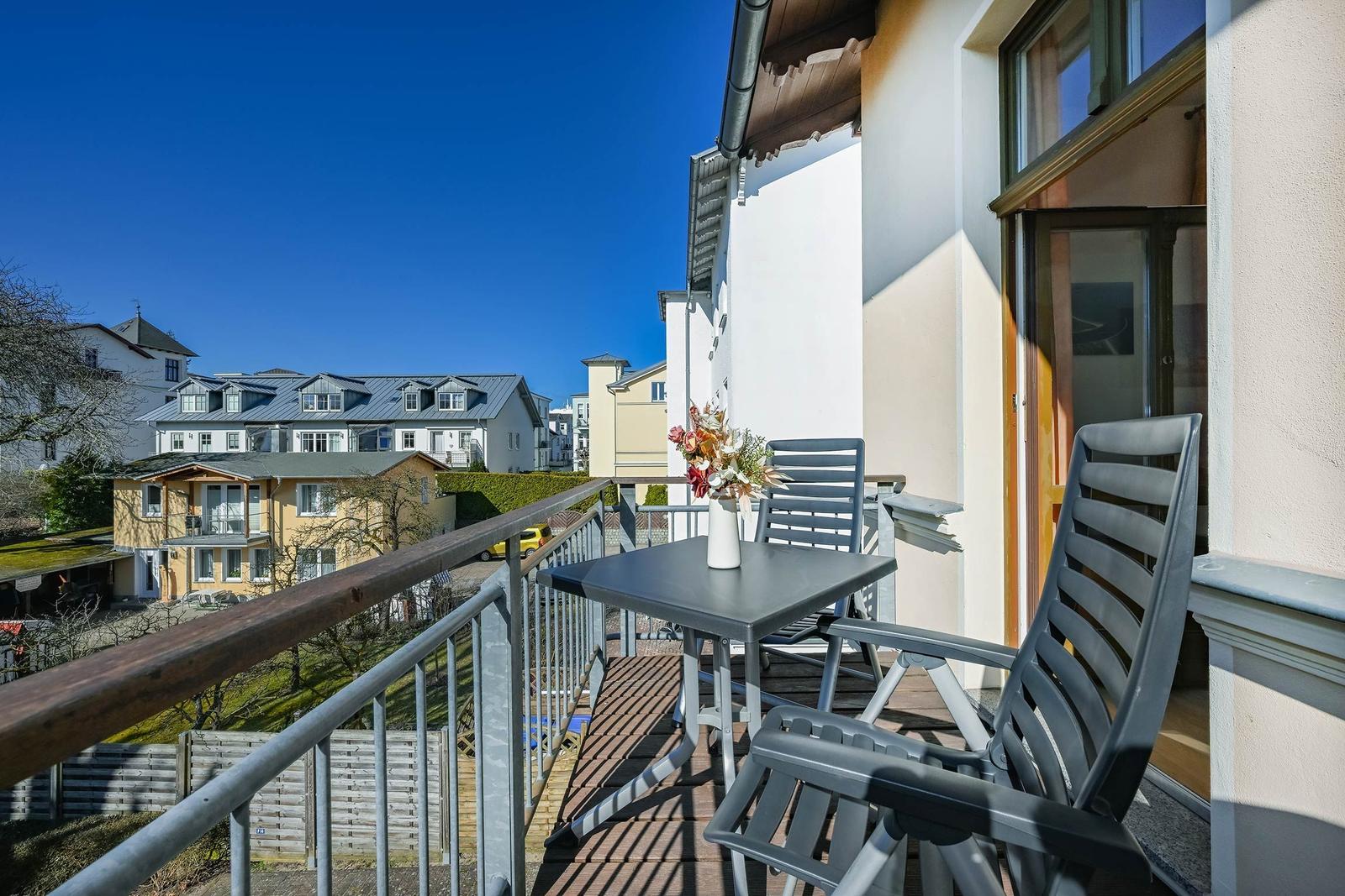 Terrasse mit Tisch und Stühlen, Blick auf Wohnhäuser und grüne Flächen.