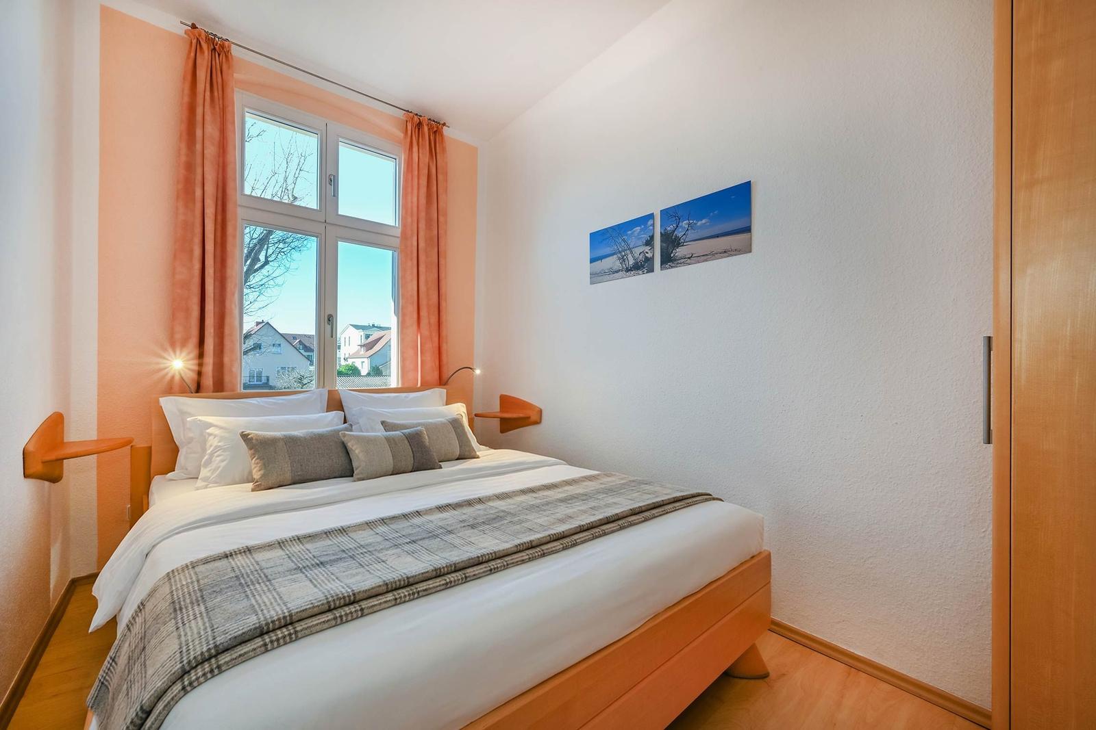 Schlafzimmer mit Bett, Fenster und Wandbildern.