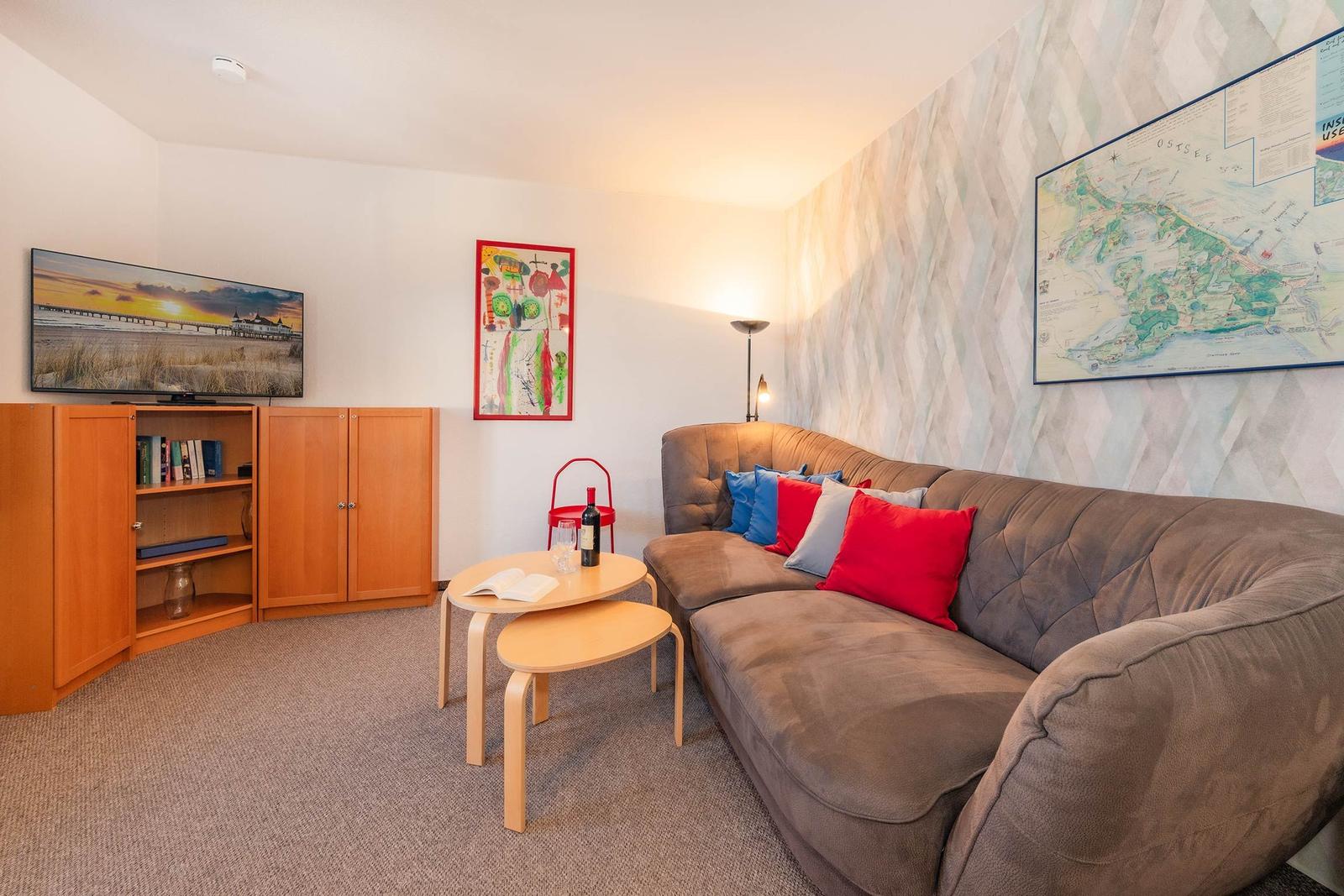 Wohnzimmer mit Sofa, Couchtisch und Fernseher an Wand