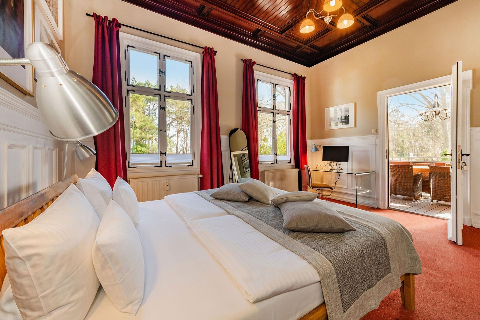 Schlafzimmer mit Doppelbett, rotem Teppich und Blick auf Balkon